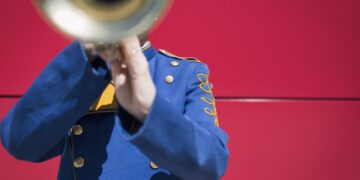Señor con uniforme azul tocando una trompeta